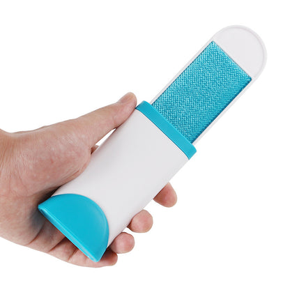 Hand holds blue mobile travel fur brush to remove pet hairs from dog